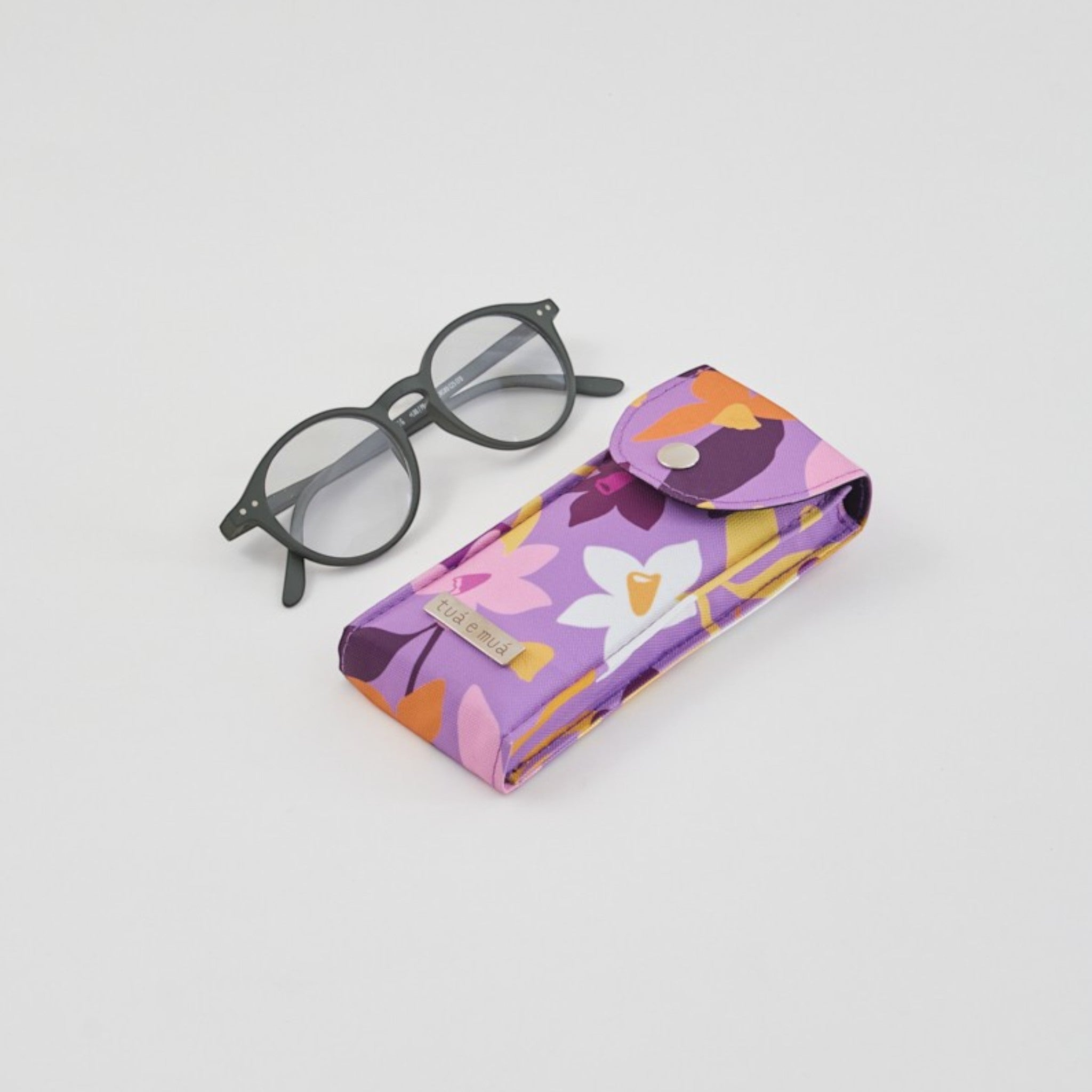 Funda de lona impermeable morada con estampado floral para gafas, interior de algodón suave, cierre de broche. Marca tuá e muá.