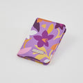 Porta pasaporte Narcisa de tuá e muá en lona impermeable con estampado floral morado, blanco y amarillo. Ideal para viajes.