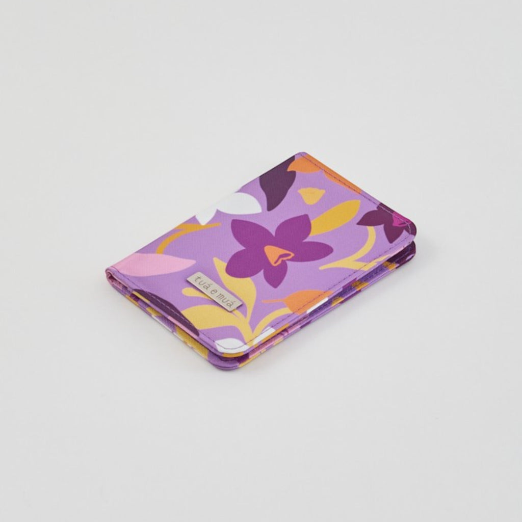 Porta pasaporte Narcisa de tuá e muá en lona impermeable morada con estampado floral, compartimentos para documentos y tarjetas.
