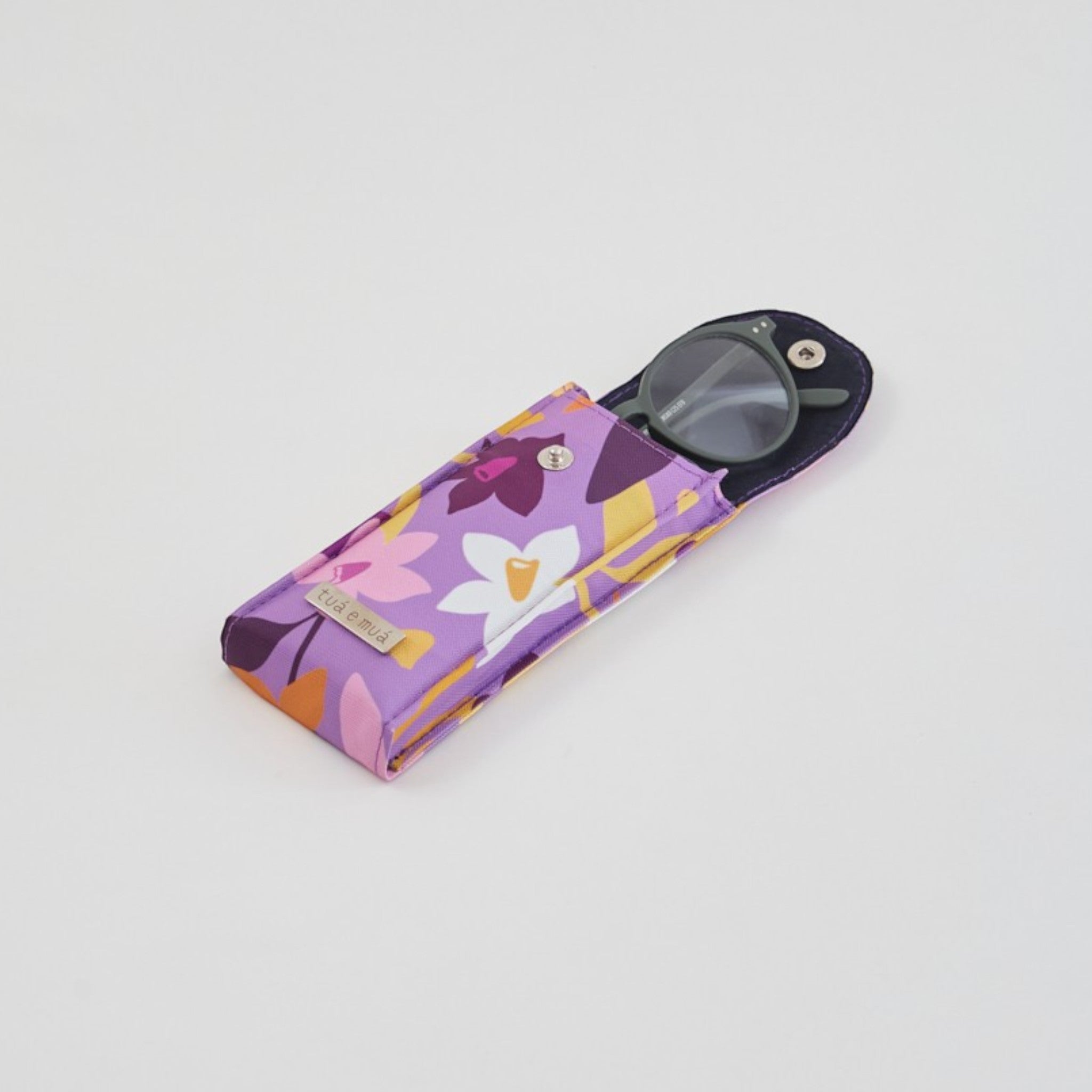Funda rígida de lona impermeable morada con estampado floral para gafas, forro interior de algodón suave y cierre de broche. Marca: tuá e muá.